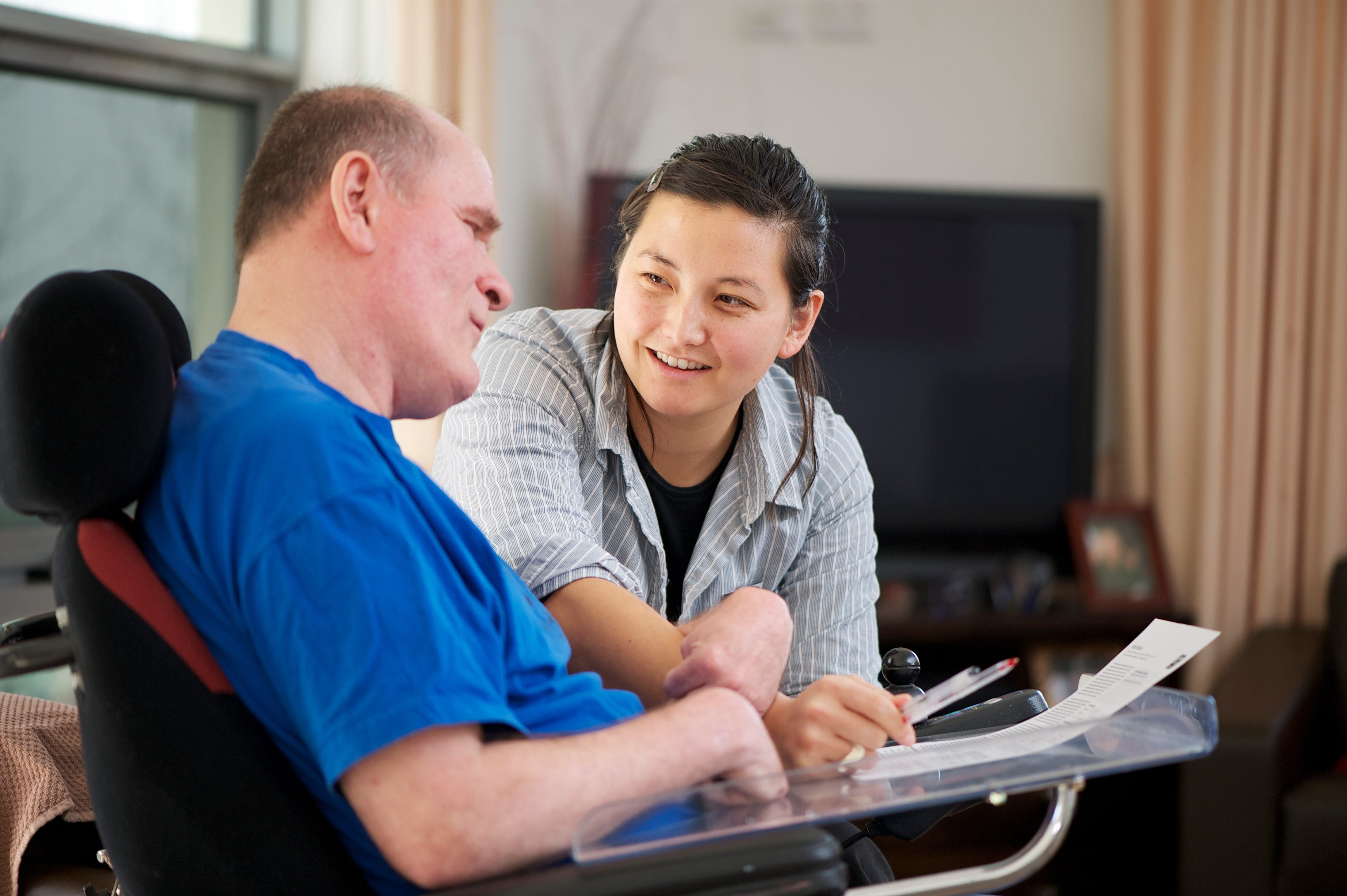 Staff assisting a man with disability to fill form